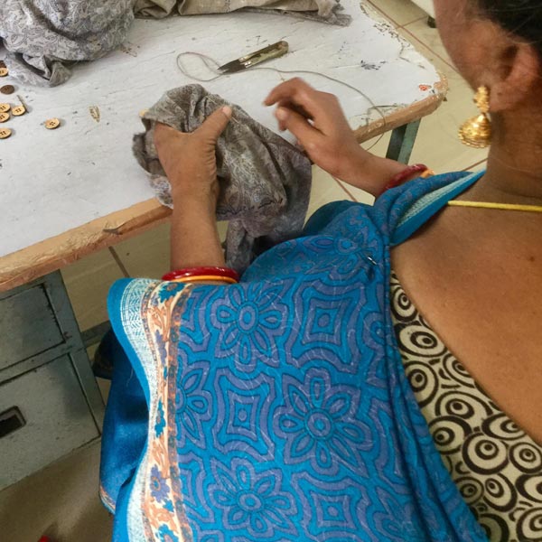 Femme en sari bleu cousant une étoffe