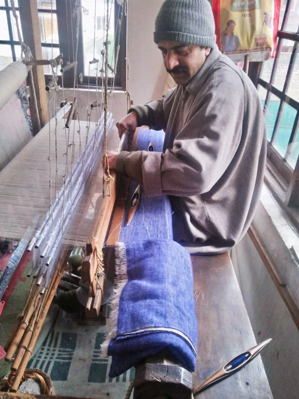 Tisserand sur un métier à tisser de cachemire bleu