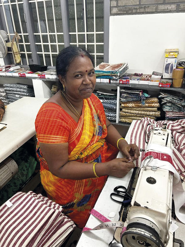 Femme en sari rouge dans un atelier de couture en Inde, pour un artisanat d'exception